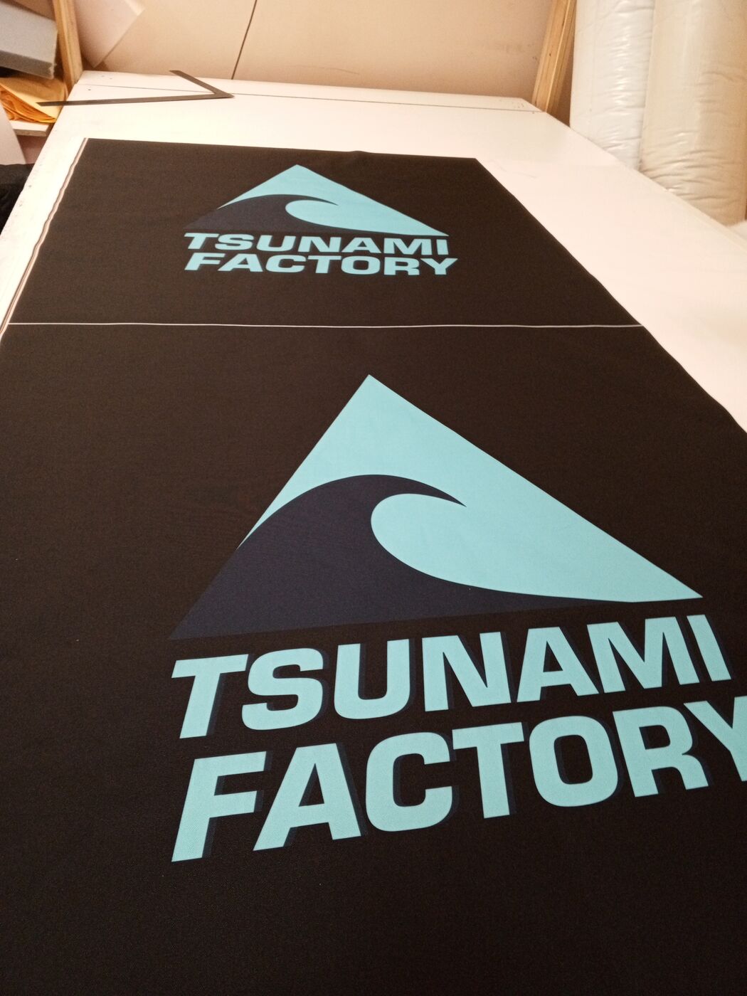 Чёрная ткань с бирюзовым логотипом Tsunami Factory — печать для подушек
